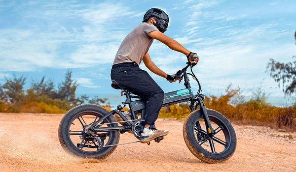 Un homme monte un vélo électrique Fiido M1 Pro Fat Tire sur le sable