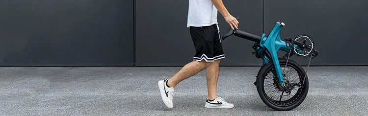 Un homme sort en poussant un vélo électrique pliant Fiido X plié
