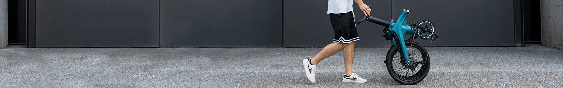 Un homme sort en poussant un vélo électrique pliant Fiido X plié