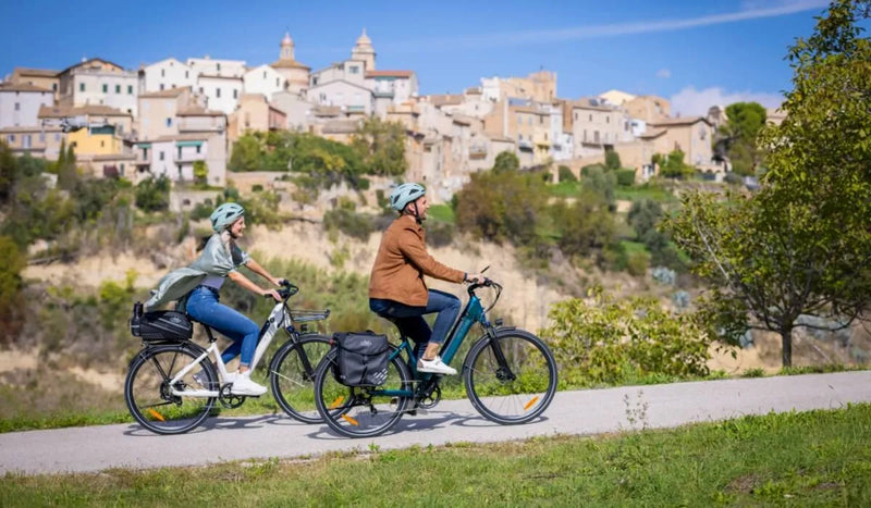 Un homme et une femme montent une côte sur des vélos électriques Fiido C11.
