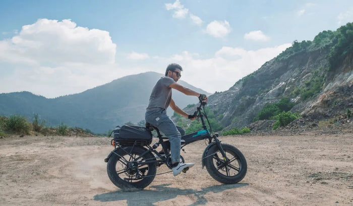 Un homme conduit un gros vélo Fiido M1 Pro à travers les montagnes.