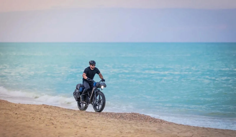 Un homme conduit un vélo électrique Fiido Titan au bord de la mer.