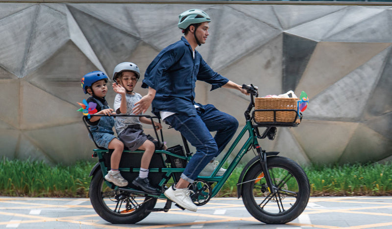 Un homme conduit un vélo électrique Fiido T2 avec deux enfants