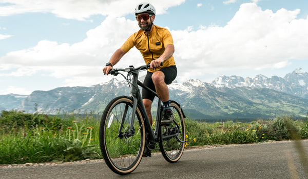 Un homme conduit son vélo électrique Fiido C21 au milieu d'un paysage montagneux.