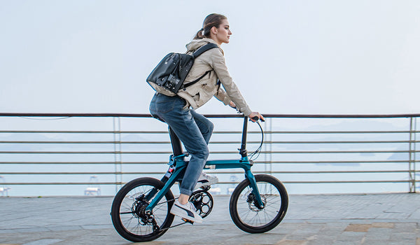 Femme conduisant un vélo électrique Fiido X sur une promenade.