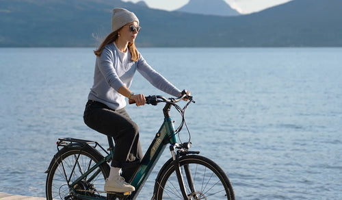 Femme chevauchant un vélo électrique Fiido C11pro au bord du lac