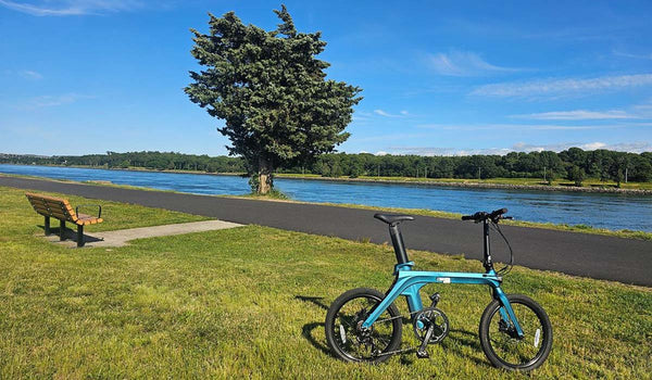 Le vélo électrique Fiido X garé près d'un sentier paisible au bord de la rivière, prêt pour une balade pittoresque.