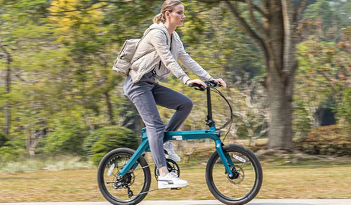 Une femme conduit un vélo électrique Fiido X dans un parc luxuriant