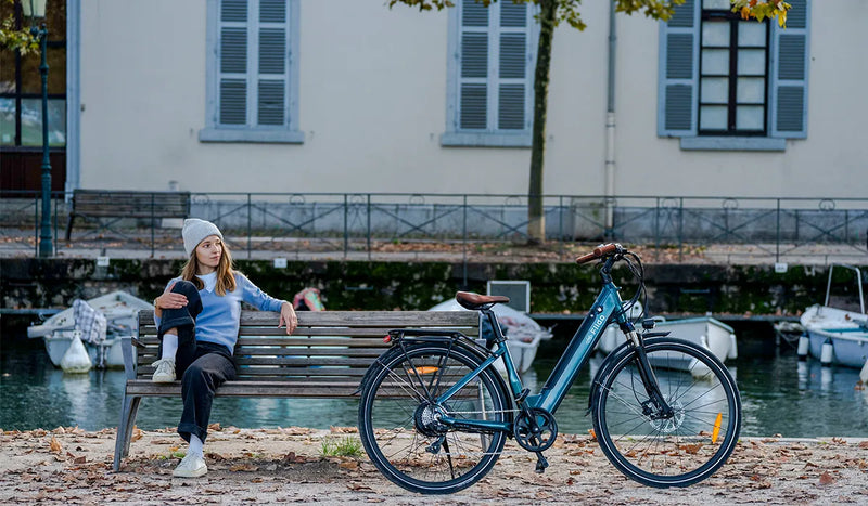 Une femme assise sur un banc de parc regarde un vélo électrique Fiido C11pro