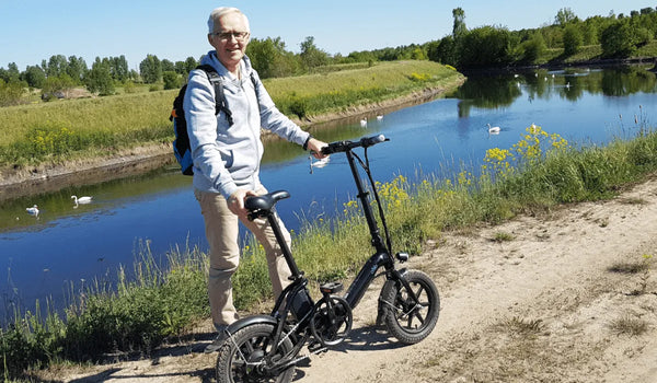 Un vieil homme conduit un vélo électrique Fiido D3 Pro près de la rivière.