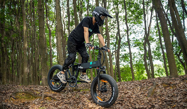 Un cycliste parcourt un sentier forestier sur un vélo électrique Fiido M1pro.