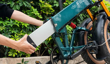 Un homme retire la batterie externe d'un vélo électrique Fiido M1 PRO.