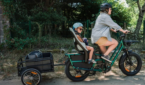 Vélo électrique cargo Fiido T2 transportant des enfants, avec une femme à vélo par une journée ensoleillée