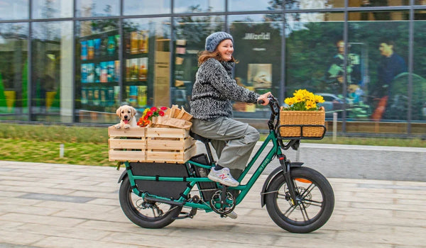 Une femme roule sur un vélo cargo électrique Fiido T2 vers le centre-ville pour faire des achats
