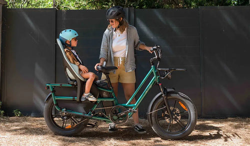 Une femme utilise un vélo électrique Fiido T2 avec un siège enfant arrière.