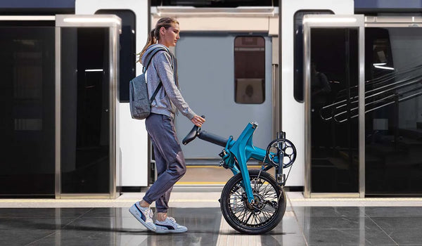 Une femme marchant en poussant un vélo électrique pliant