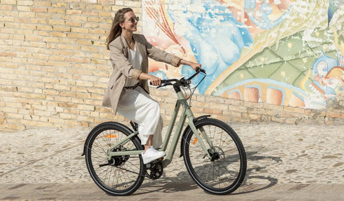 Une femme conduit un vélo électrique Fiido C700 dans la rue.