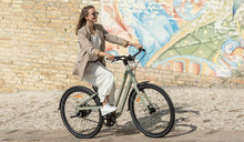 Une femme conduit un vélo électrique Fiido C700 dans la rue.