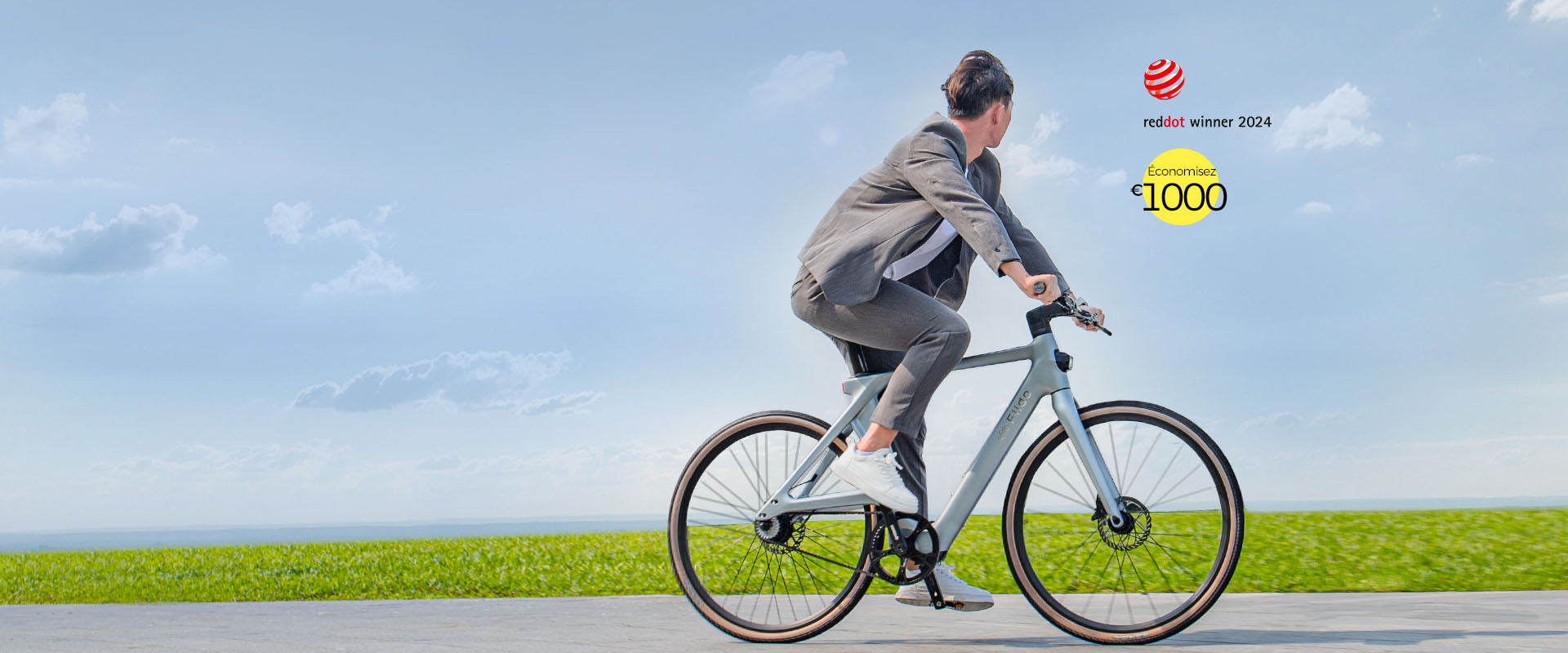 Un homme en vêtements gris roule sur un vélo électrique Fiido Air sur une route - pc